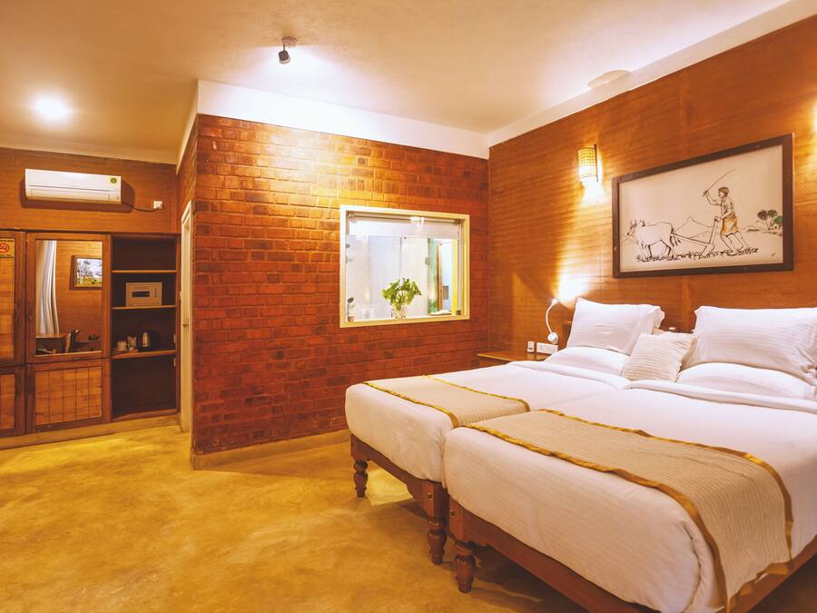 Habitación de hotel con pared de ladrillo, una cama grande, una ventana con planta y un cuadro en la pared.