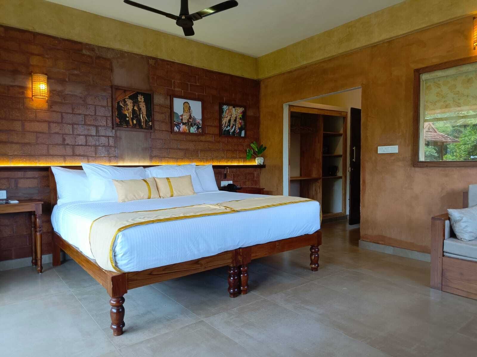A spacious bedroom with a large bed, a wooden headboard, and a brick accent wall.