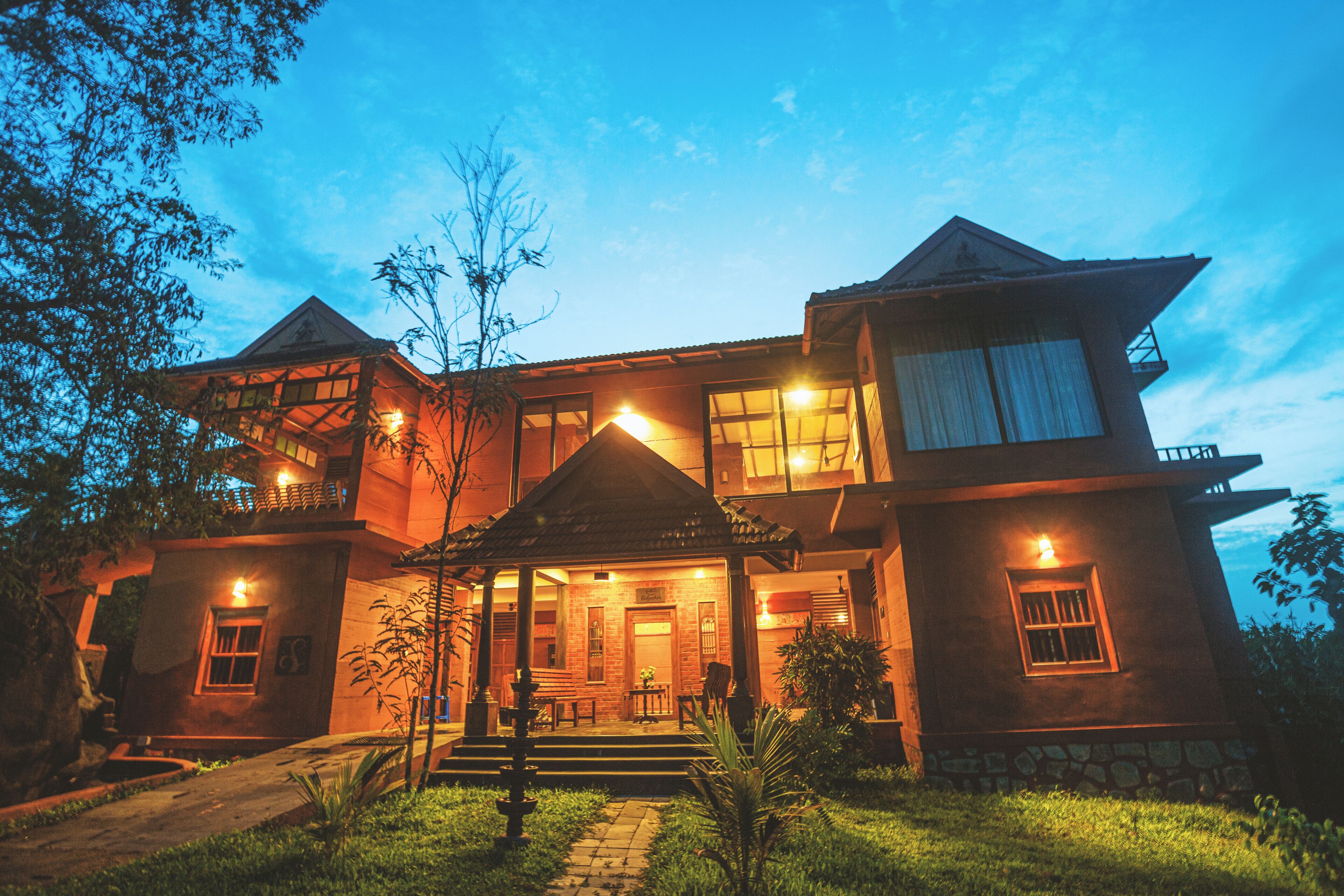 A large, two-story house with a well-lit entrance, a small porch, and a stone foundation.