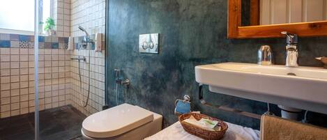 A bathroom with a shower, toilet, sink, and a towel rack.