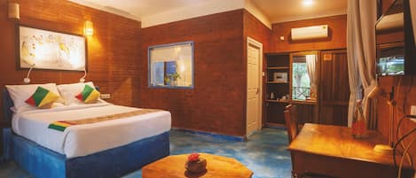 A hotel room with a bed, a wooden table, a ceiling fan, and a window with curtains.