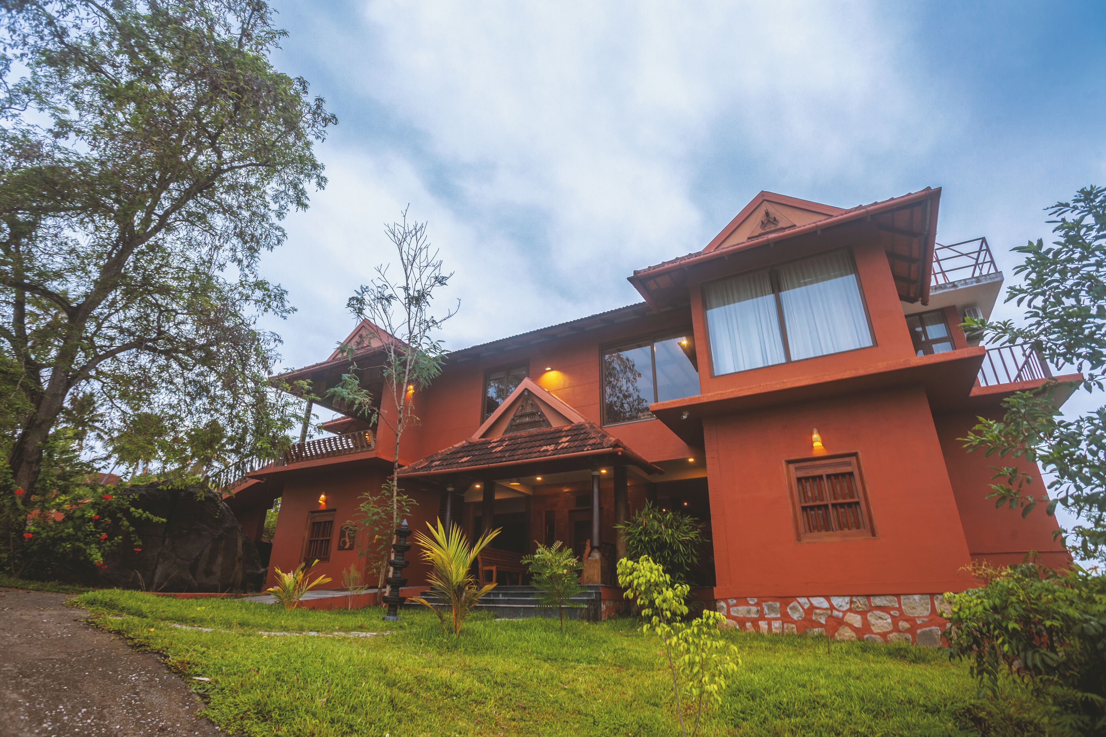 A two-story building with a red exterior, a balcony on the upper floor, and a small porch area.