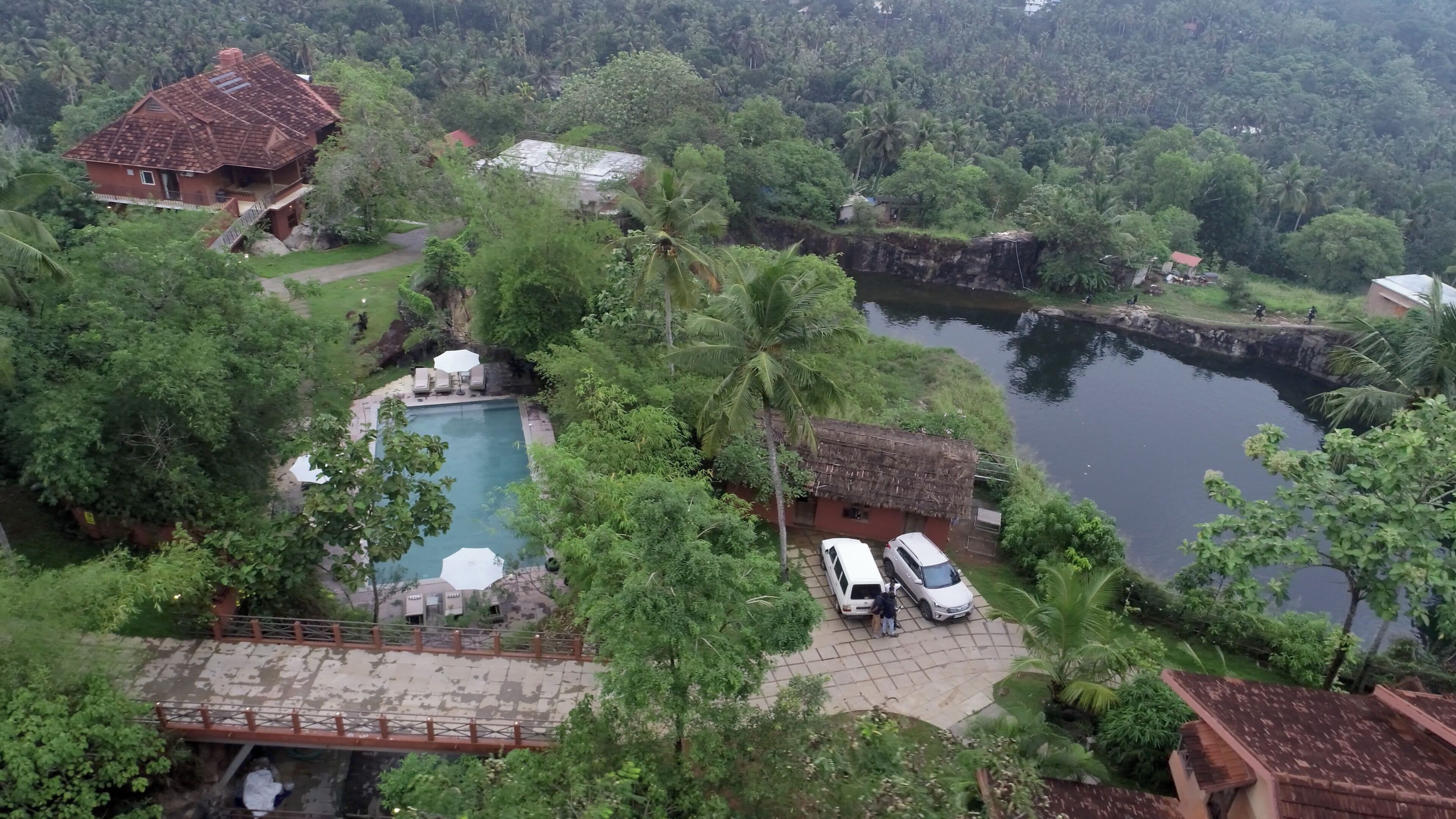 A resort with a swimming pool surrounded by lush greenery and a river.