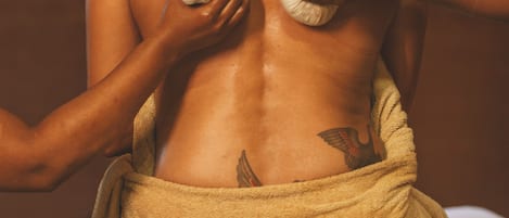 A person receiving a massage with a towel wrapped around their lower back.