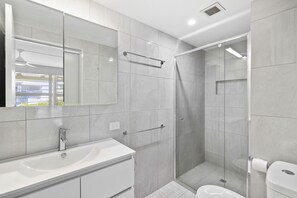 Features a sleek vanity, glass-enclosed shower, and a separate toilet.