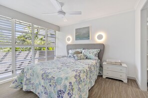 Relax in this serene bedroom with a large bed, nightstand, and ceiling fan.