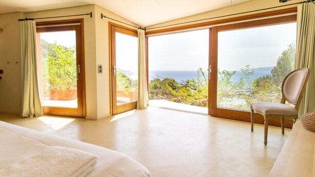Un dormitorio con una cama grande, una silla y vistas al océano.