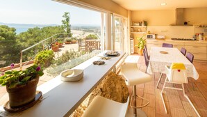 Un balcón con plantas en macetas, un comedor con mesa y sillas, y una cocina con armarios y electrodomésticos.