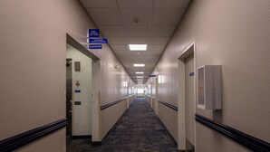 A hotel hallway with directional signs for guest services, an elevator, and a fire alarm.