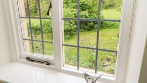 Una ventana con un diseño de cuadrícula, un alféizar blanco y un pequeño adorno en el alféizar.