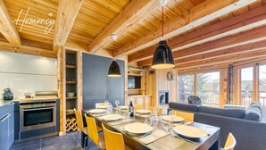 Uma cozinha moderna com forno embutido e uma área de jantar com uma mesa comprida posta para seis.