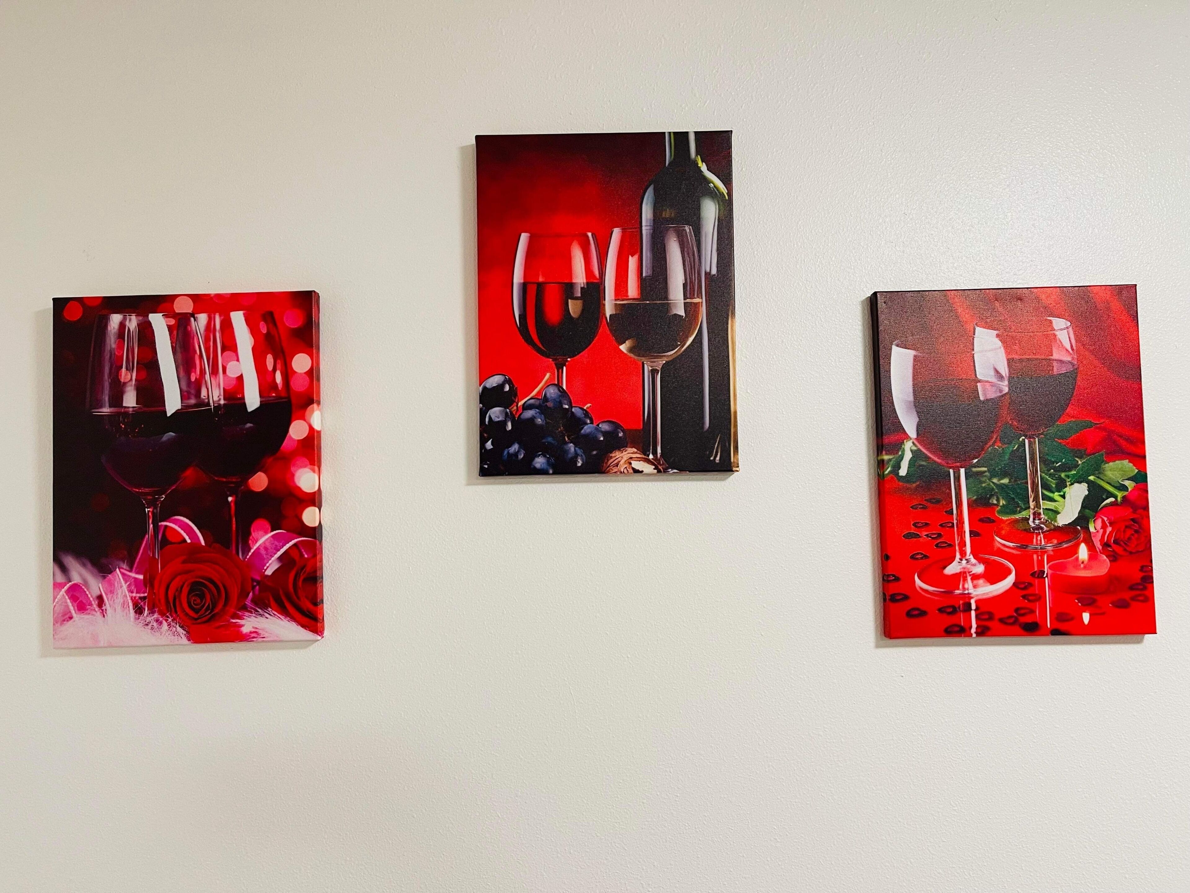 Three framed paintings of wine glasses on a wall.