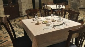 A dining area with a square table set for four, surrounded by wooden chairs. - Barabagh Deogarh (Devgarh)