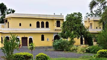 A two-story building with a yellow facade, arched windows, and a balcony.