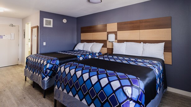 Une chambre d’hôtel avec deux lits, une tête de lit en bois et un mur bleu.