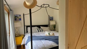 A bedroom with a four-poster bed, a wooden floor, a yellow bedside table, and a white door. - Cute Loft , Ideal Location to Bayside Camden and Belfast
Day trip to Bar Harbor! (Northport)