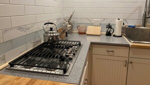 A kitchen with white subway tiles, a gas stove, a sink, and wooden cabinets. - Cute Loft , Ideal Location to Bayside Camden and Belfast
Day trip to Bar Harbor! (Northport)