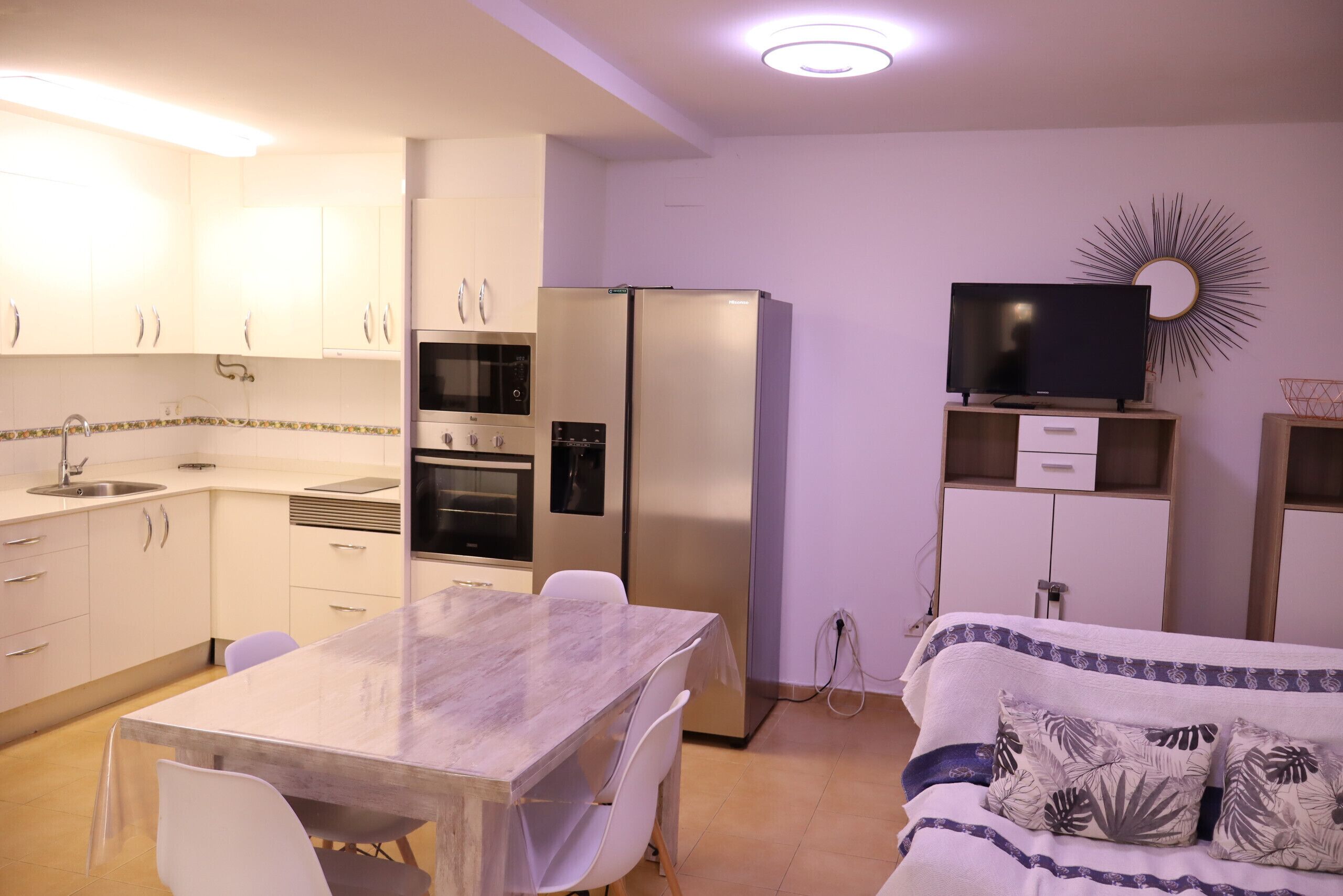 A compact living space with a kitchenette, a dining area, and a bed.