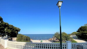 Une terrasse en bois avec une clôture blanche, un lampadaire en métal et une vue sur la mer.
