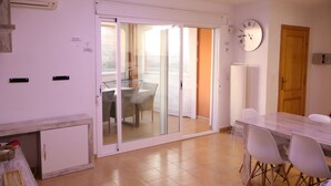Une cuisine moderne dotée d’un four encastré, un coin repas avec une table et des chaises, et une porte-fenêtre coulissante donnant sur un balcon.