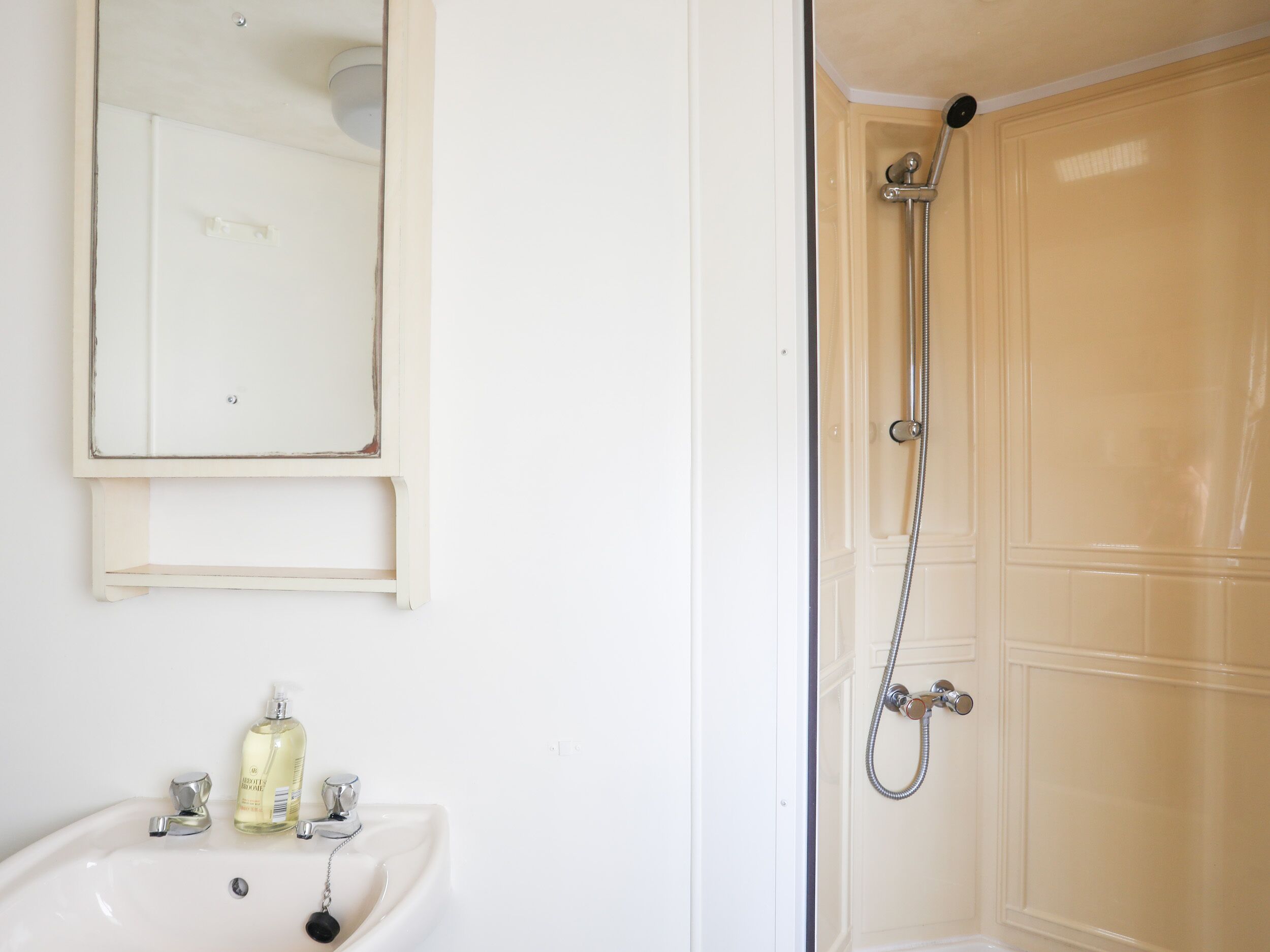 A bathroom with a white sink, a mirror, and a shower enclosure.