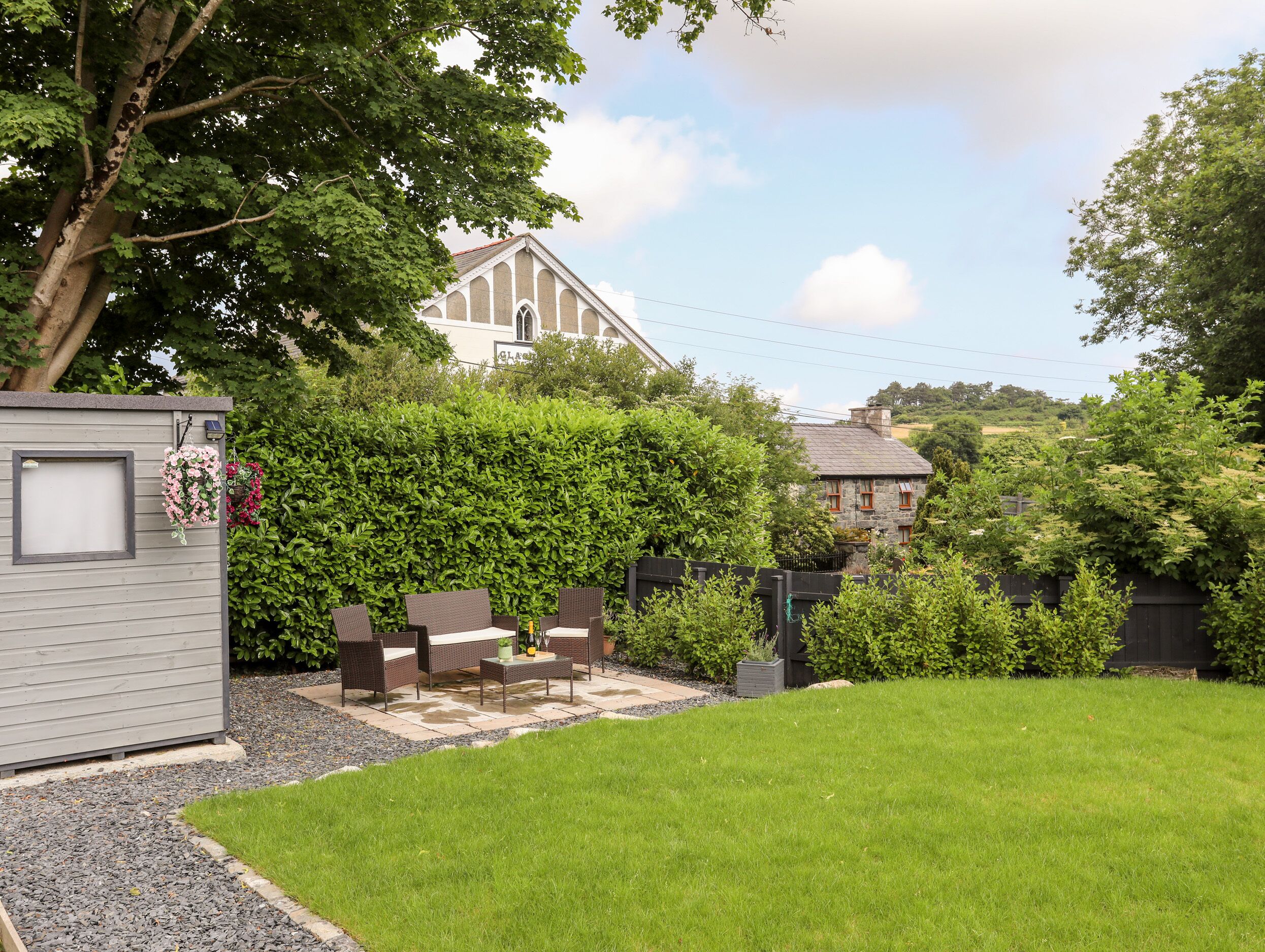 A backyard with a patio, seating area, and a hedge.