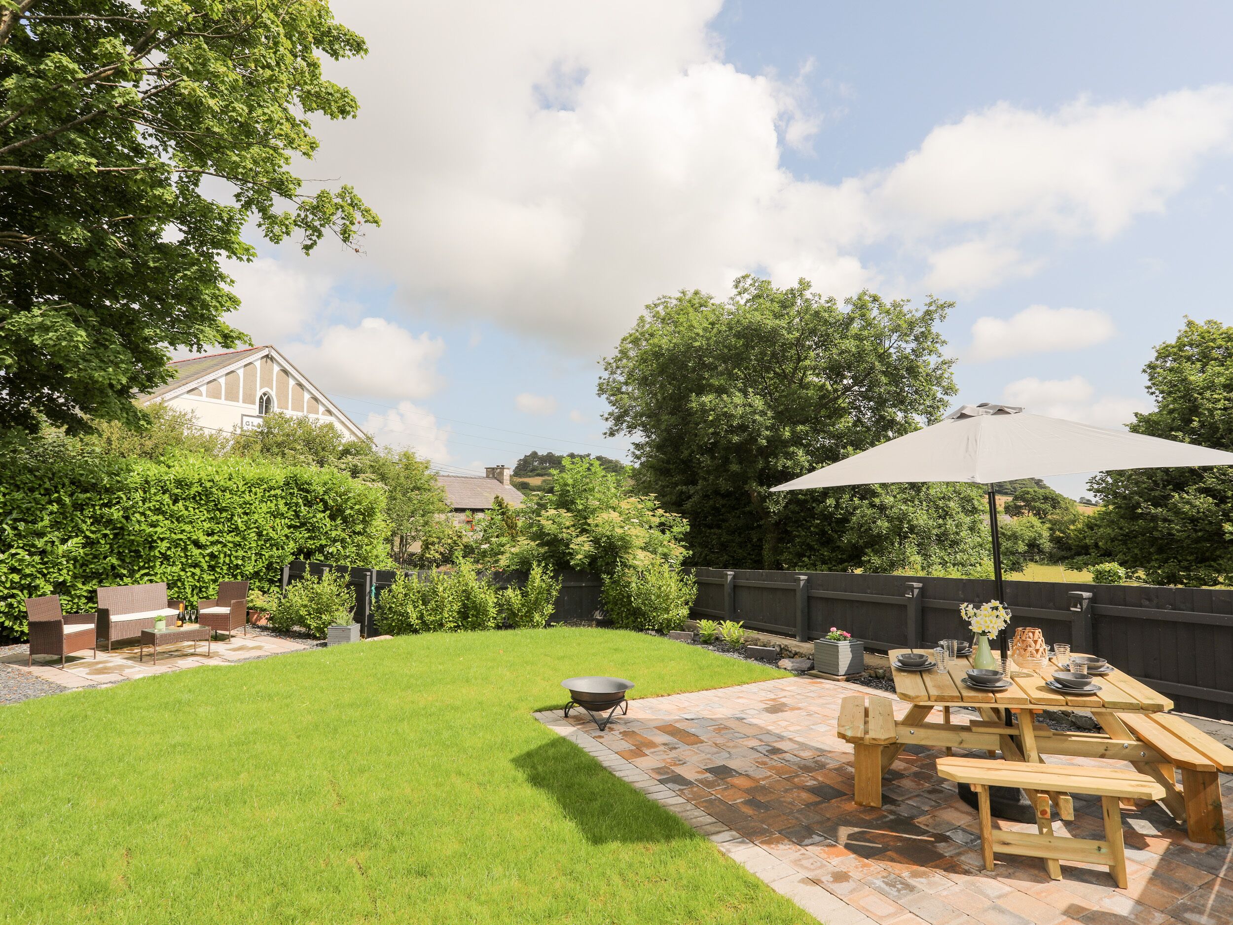 A backyard with a patio area, a wooden table, and a large umbrella.