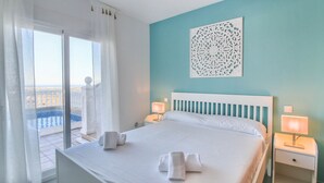 A hotel room with a bed, two bedside tables with lamps, a large window with curtains, and a decorative wall piece. - Villa with panoramic views all inclusive La Sella DJ (Pedreguer)