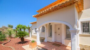 A house with a white exterior, a tiled roof, and a stone pathway leading to the entrance. - Villa with panoramic views all inclusive La Sella DJ (Pedreguer)