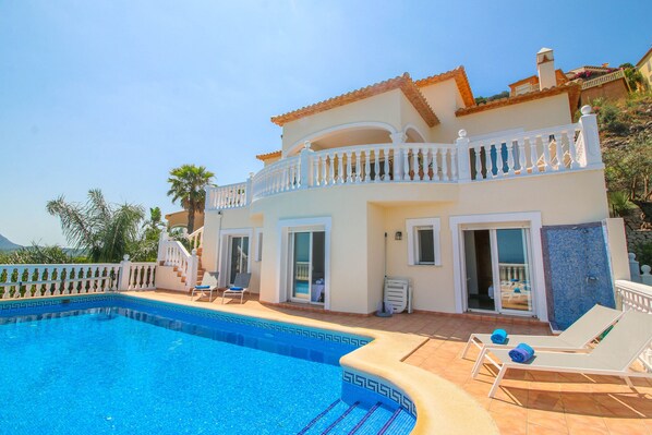 Una casa a due piani con piscina, un balcone e una scala che conduce al piano superiore.
