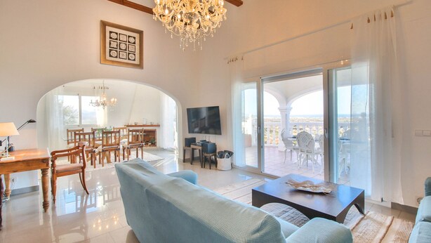 A spacious living room with a large TV, comfortable seating, a chandelier, and a balcony with a city view. - Villa with panoramic views all inclusive La Sella DJ (Pedreguer)