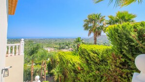 A balcony with a view of a coastal landscape, including palm trees and a distant view of the sea. - Villa with panoramic views all inclusive La Sella DJ (Pedreguer)