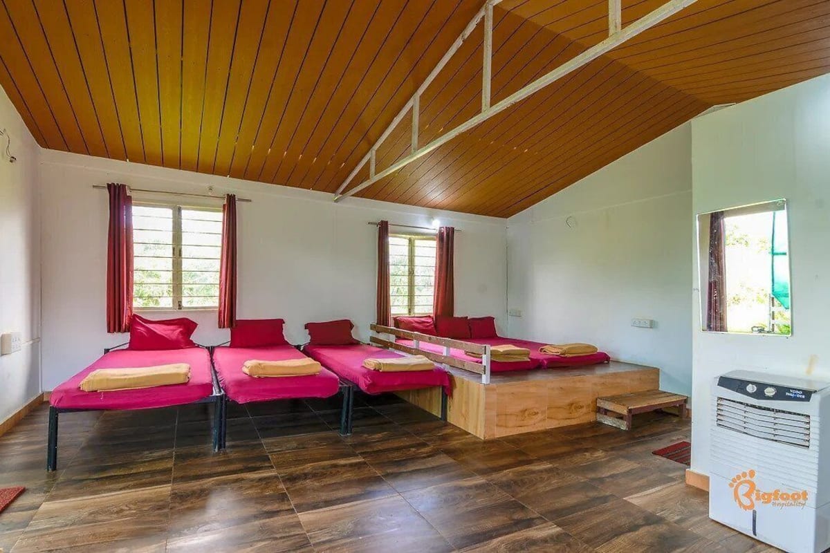 A room with four beds, wooden flooring, and a ceiling with wooden beams.