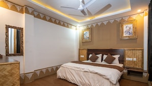 A hotel room with a large bed, a ceiling fan, and decorative wall trim. - Mussoorie (Dehradun)