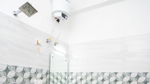 A bathroom with a white sink, a mirror, a showerhead, and patterned tiles. - Mussoorie (Dehradun)