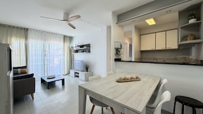 Una sala de estar moderna con una mesa de comedor, un sofá, un televisor y un ventilador de techo.