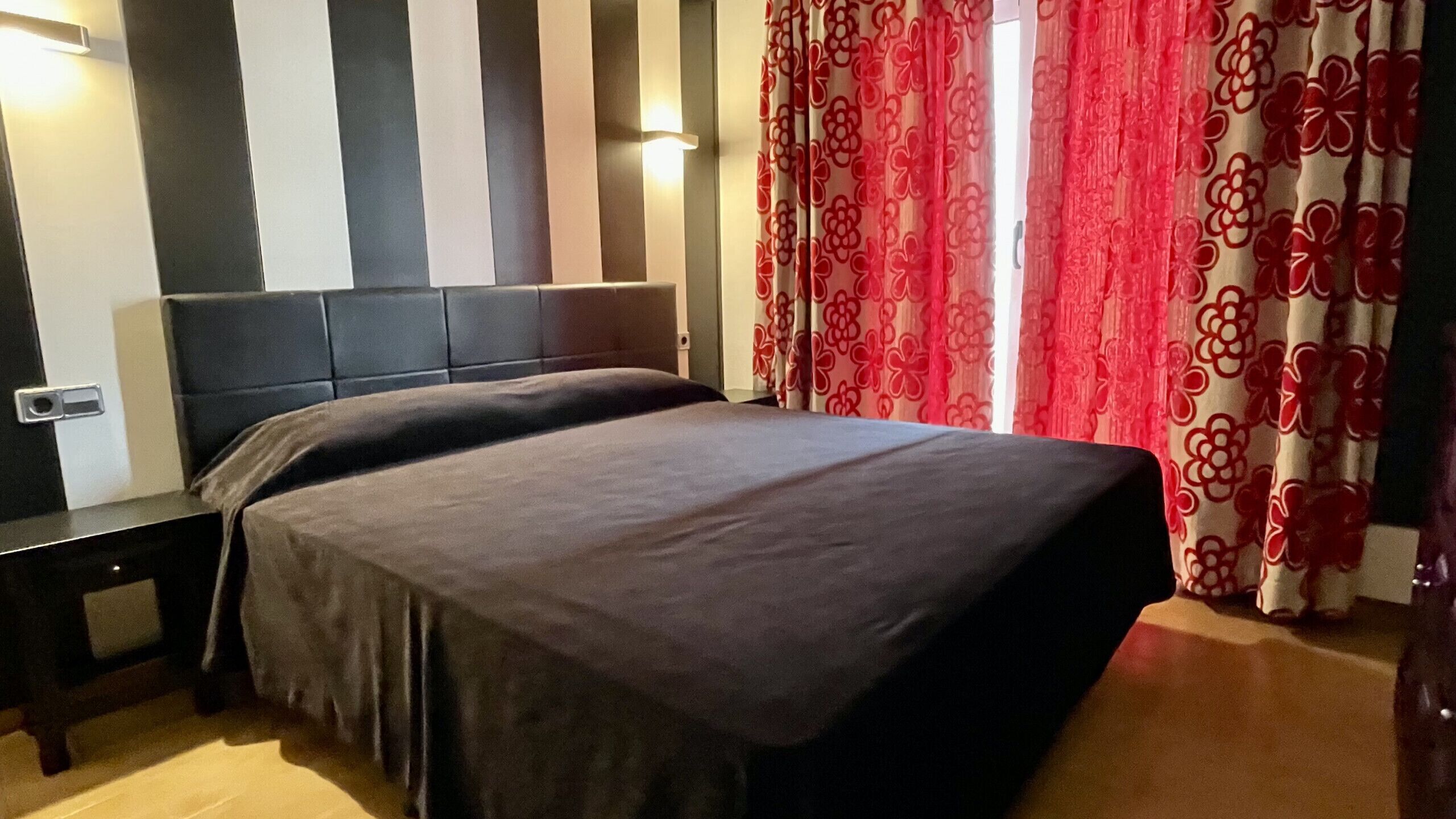 Une chambre à coucher avec un lit, une table de chevet et un mur orné de rayures verticales.