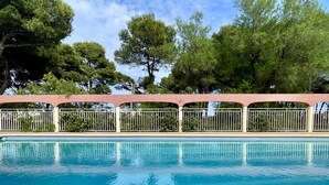A swimming pool with a clear blue water surface, surrounded by a white fence and a pink canopy. - SALLES BEACH 2 (Estartit)