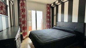 Un dormitorio con cama, cortinas y vista a través de una puerta.