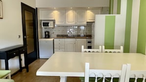 A compact kitchen with white cabinets, a microwave, a coffee maker, and a dishwasher. - SALLES BEACH 3 (Estartit)