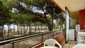 A balcony with a table and chairs, overlooking a beach with trees and a clear view of the sea. - SALLES BEACH 3 (Estartit)