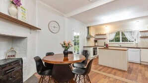 Une cuisine moderne dotée d’un îlot central, de meubles blancs et d’un coin repas avec une table ronde et des chaises.