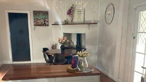 Une cuisine dotée d’un plan de travail en bois, de meubles blancs et d’un coin repas avec des chaises et une table.