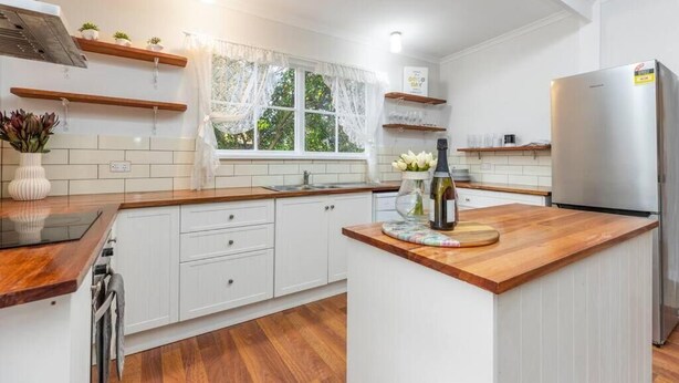Une cuisine moderne avec des meubles blancs, des plans de travail en bois et un réfrigérateur en acier inoxydable.