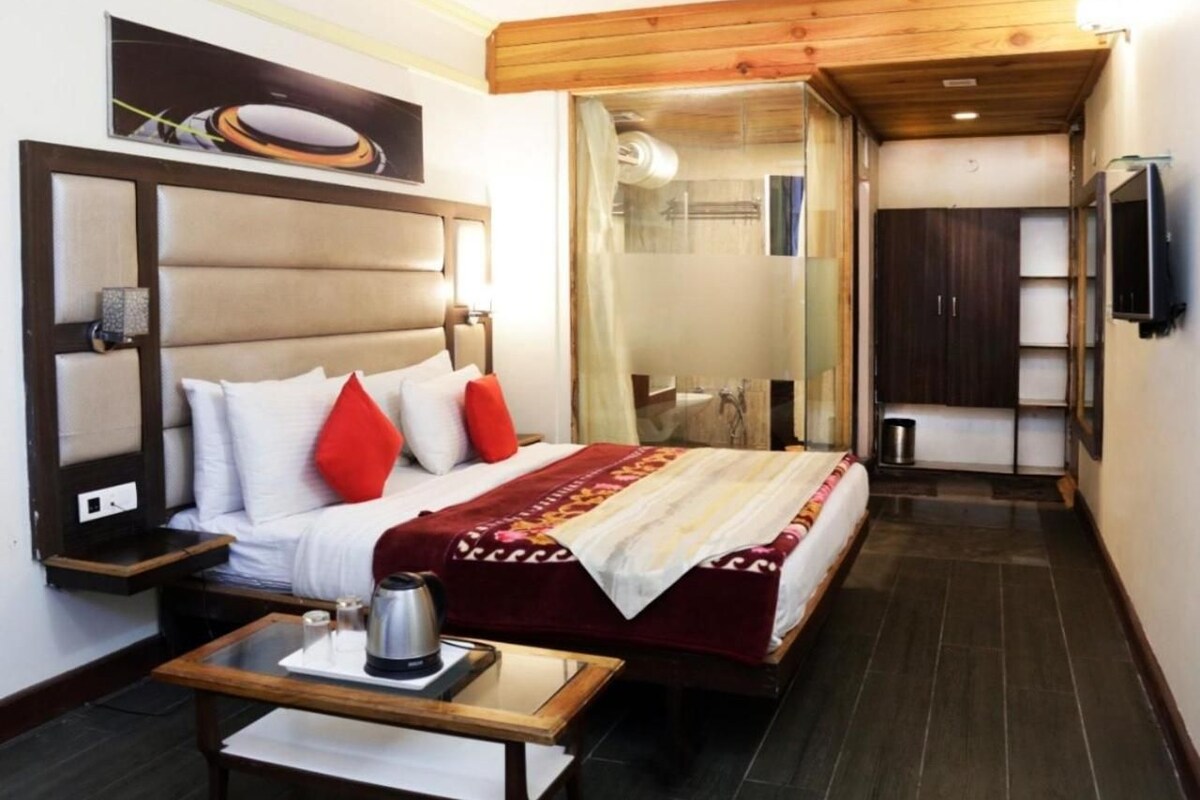 Une chambre d’hôtel avec un lit, une table de chevet et une petite table sur laquelle se trouve une bouilloire.