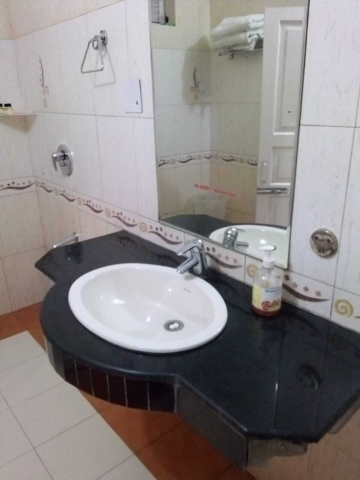 A bathroom with a white sink, black countertop, and a mirror.