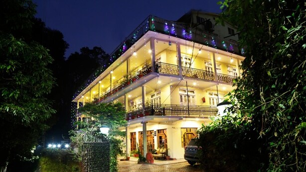 Um hotel de vários andares com varandas, entrada pavimentada e acesso por portão.