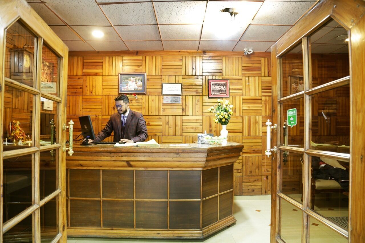 A reception desk with a man at the counter, wooden paneling on the walls, and framed certificates.
