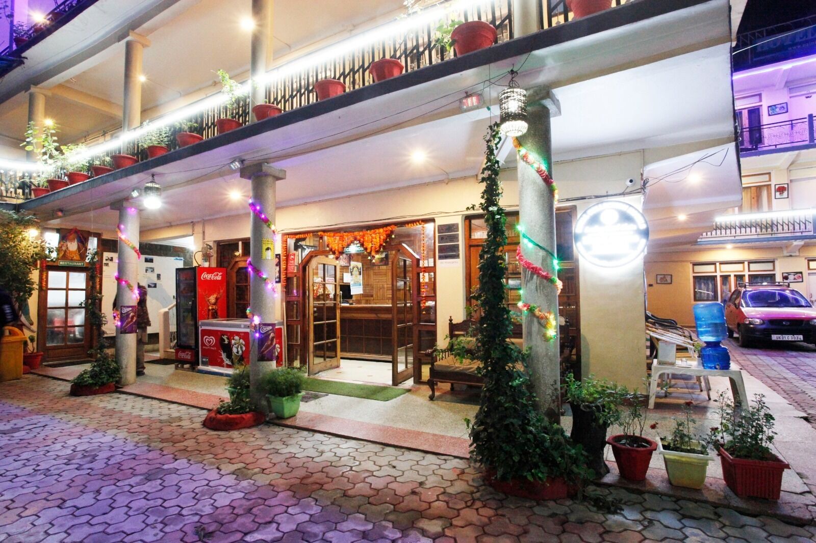 L’entrée d’un hôtel avec un réfrigérateur Coca-Cola, des plantes en pot et un escalier.