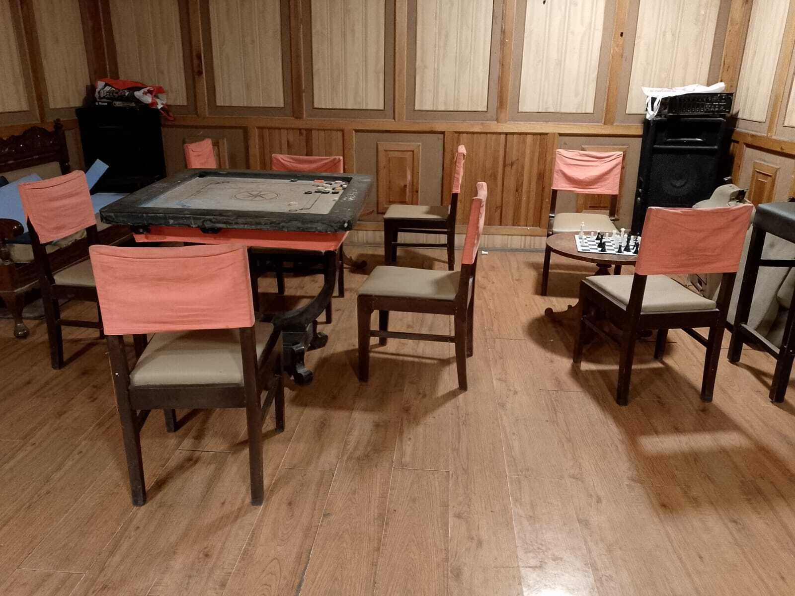 Ein Zimmer mit Holzboden, einem Tisch mit Schachbrett und mehreren Stühlen.